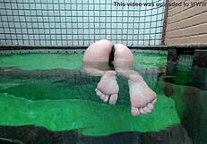 Latina wife enjoys a relaxing bath in the hotel pool.