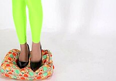 Beautiful legged woman steps on cushion with high heels, showcasing her shoe fetish.