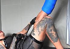 Asian goddess with tattoos and piercings rocks dominatrix outfit with short cast legs.