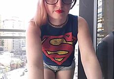 A hot gamer girl in clothes flashes her big tits on the balcony outdoors