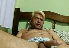 Two gay men engage in passionate anal sex with kissing and oral play in a private bedroom setting.