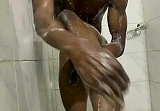 muscular gay bodybuilder showers barefoot in close up