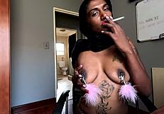 The desi girl in hijab casually smokes while her nipples are clamped in stockings.