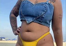 African woman flashes and arouses guy on beach.