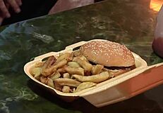 A blonde woman experiences double penetration in a group sex scenario with anal elements.