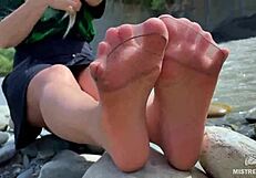 goddess teases with tan nylon soles and toes by the riverside, close-up fetish delight