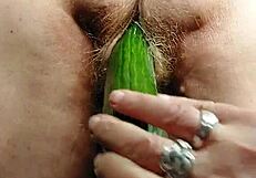Granny intensely fucks her hairy pussy with a thick cucumber.