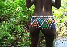 skinny ebony girl from tribe gets taken by stream in forest outdoors.